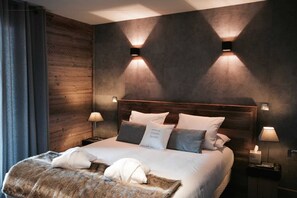 Ein modernes Hotelzimmer mit einem Holzkopfteil, zwei Nachttischlampen, einem großen Bett mit weißen Bettwäsche und einer Felldecke.