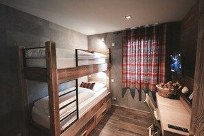 Ein Mehrbettzimmer mit Fernseher, Schreibtisch und einem karierten Vorhang.