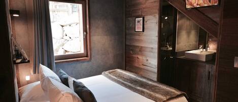 A bedroom with a bed, a window, a bathroom with a sink, and a television mounted on the wall.