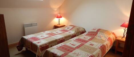 A small, cozy room with two beds, a window, and a heater.