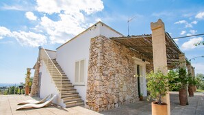 A stone house with a white exterior, a wooden staircase, and a view of the sea. - Hilly Trullo with Sea View (Leuca)