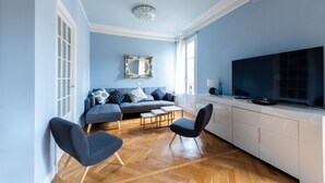 Een moderne woonkamer met een bank, twee stoelen, een televisie en een eettafel.