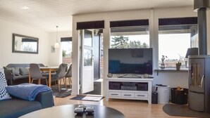 Una sala de estar moderna con una televisión de pantalla plana, un sofá, una zona de comedor y una chimenea.
