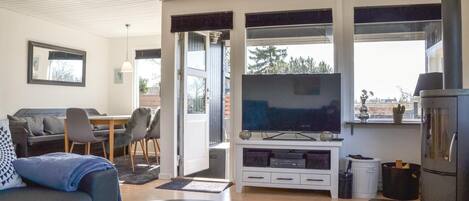 Una sala de estar moderna con una televisión de pantalla plana, un sofá, una zona de comedor y una chimenea.