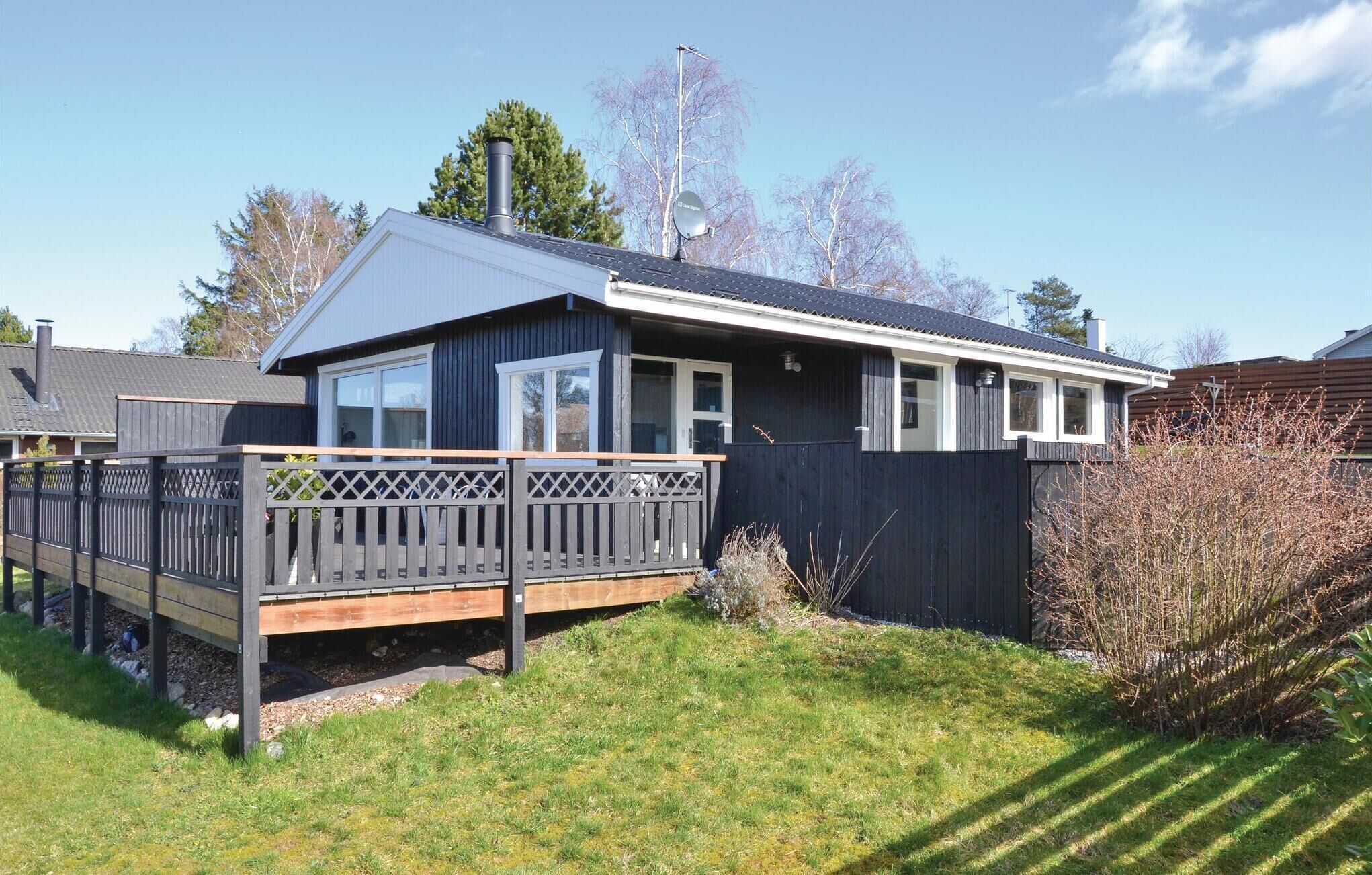 A modern house with a deck, large windows, and a chimney.