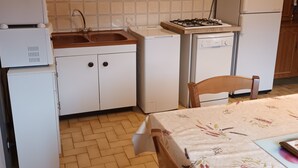A compact kitchen with white cabinets, a sink, a stove, and a refrigerator.