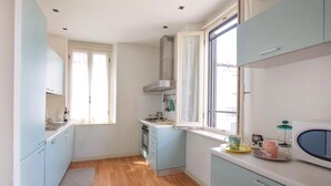 A compact kitchen with light blue cabinets, a gas stove, and a window providing natural light. - Beautiful home in Viareggio with WiFi (Viareggio)