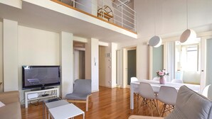 A modern living room with a flat-screen TV, a sofa, a dining table with chairs, and a balcony with a wooden railing. - Beautiful home in Viareggio with WiFi (Viareggio)