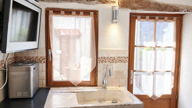 A kitchen with a built-in sink, a microwave, and a television mounted on the wall.