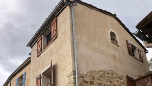 A building with a stone facade, wooden shutters, and a metal gutter.