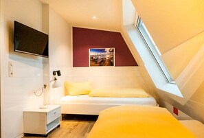 Une chambre moderne avec un lit, un bureau, une télévision et une fenêtre.