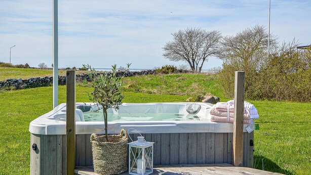 Ein Whirlpool mit Holzterrasse, einem Korbwannen und einer Laterne.