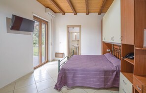 A bedroom with a bed, a TV, a wardrobe, and a bathroom visible through an open door. - Cozy home in Joppolo with WiFi (Joppolo)