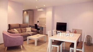 A modern living room with a sofa, a coffee table, a TV, and a dining table with chairs.