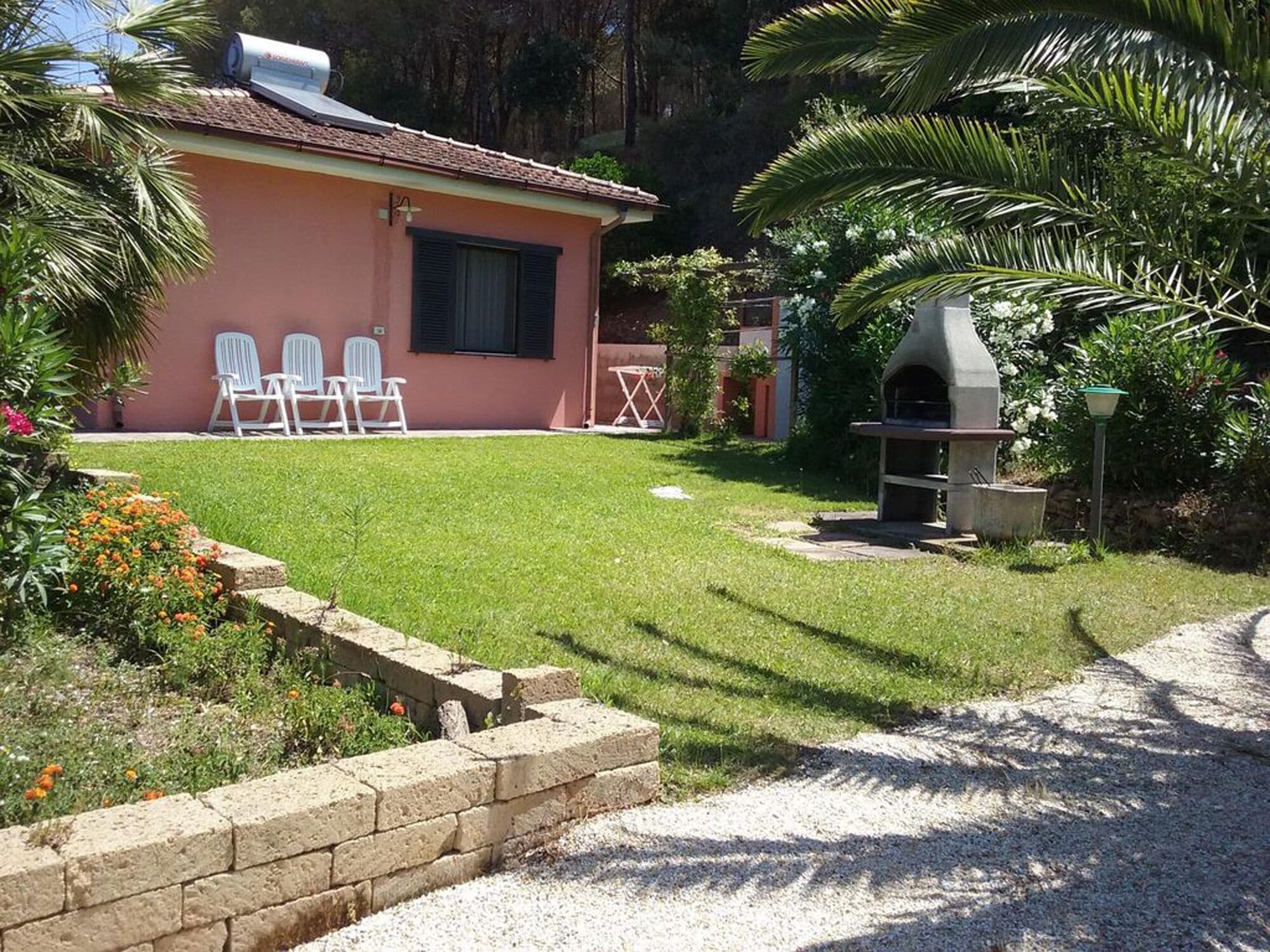 A house with a small lawn, outdoor seating, and a barbecue area.