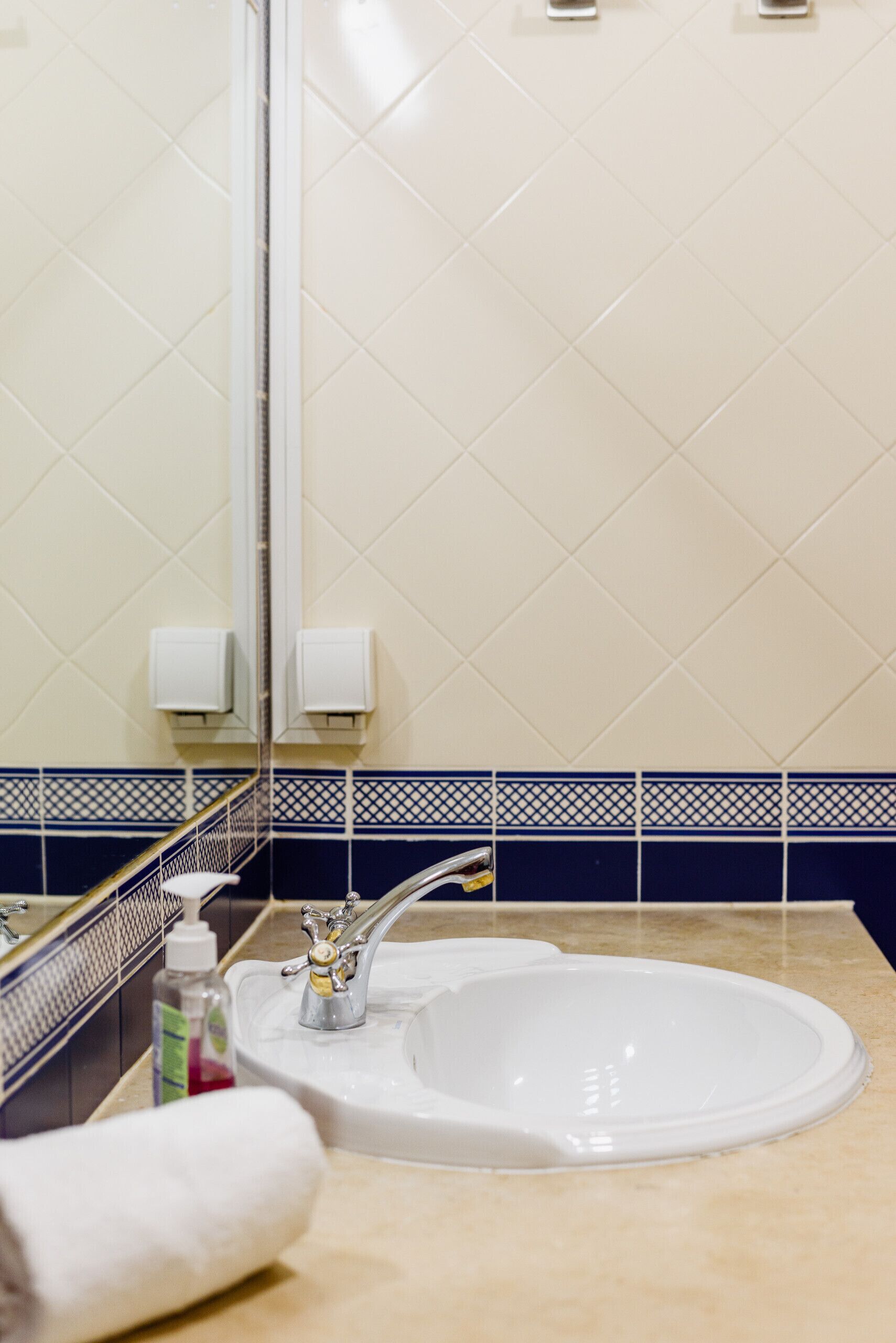 A bathroom with a white sink, a mirror, and a towel.