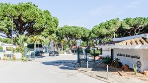 Une entrée fermée par un portail, sur laquelle on peut lire l’inscription « aldeia das acoletas », le tout étant entouré d’une végétation luxuriante et d’arbres.