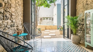 A cozy outdoor seating area with a stone wall, a small table with chairs, and a potted plant.