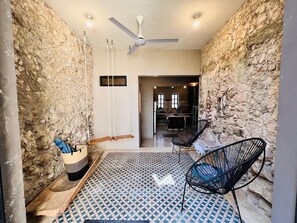 A room with a stone wall, a ceiling fan, a patterned floor, and two black chairs. - ECO-CHIC HOUSE, PRIVATE POOL, CULTURE, CENTRO (Mérida)