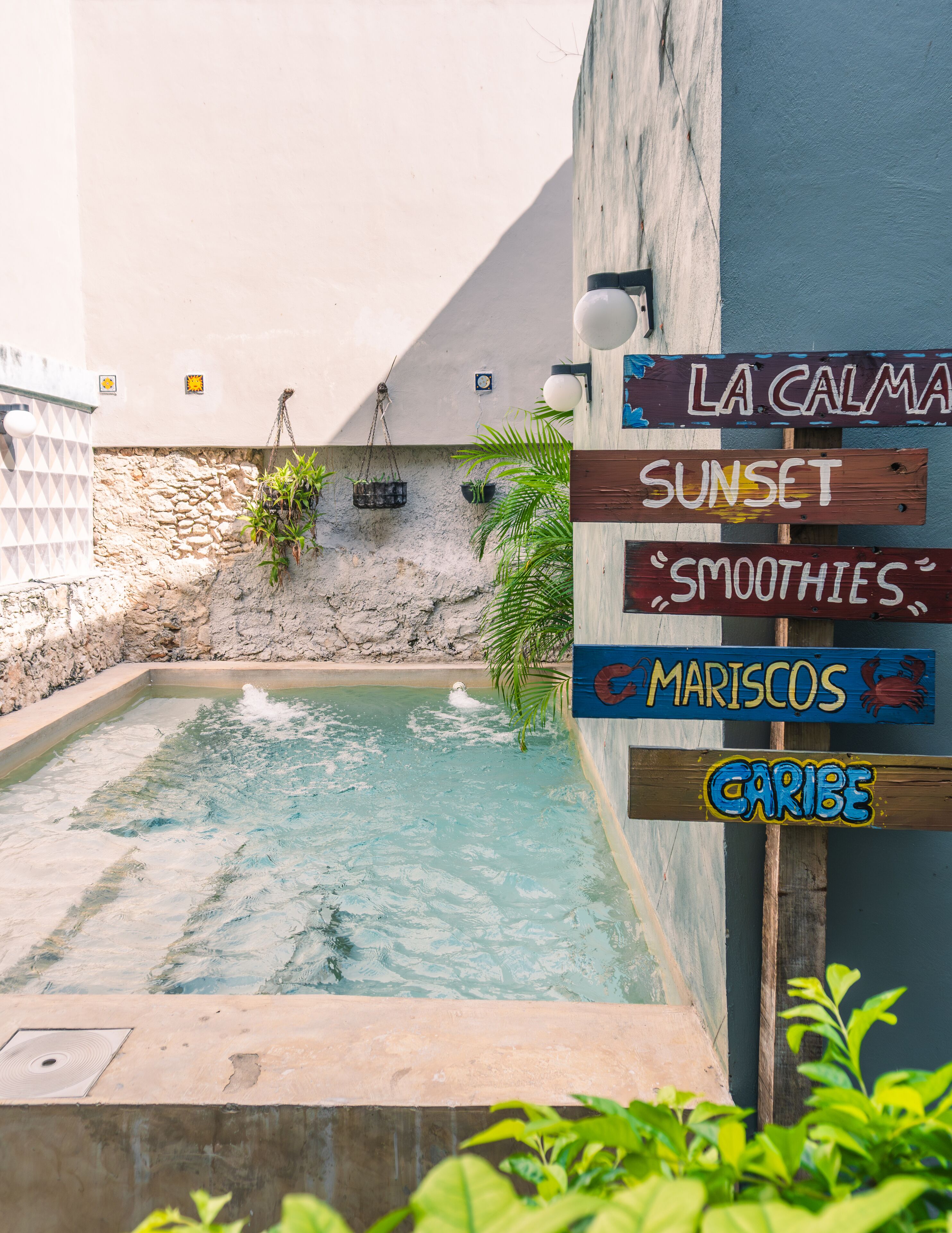 Un espace piscine agrémenté d’un panneau indiquant : « La Calma, cocktails au coucher du soleil, fruits de mer des Caraïbes ».