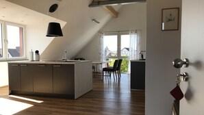 Eine moderne Küche mit Kochinsel, Holzboden und Essbereich mit Stühlen.