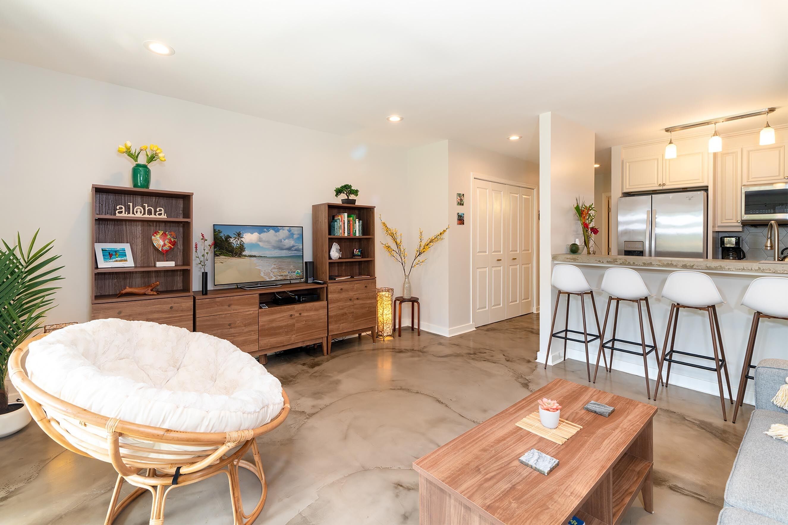 A modern living room with a large round chair, a wooden coffee table, and a bookshelf.