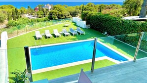 A swimming pool with lounge chairs and a view of the sea.