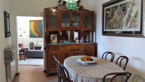 A dining area with a table set for four, a wooden cabinet with glass doors, and a painting on the wall.