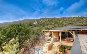 A modern house with a covered patio, outdoor seating, and a view of a mountainous landscape. - LES PIEDS DANS L'EAU Jacuzzi and beach for 2 to 8 people (Coti-Chiavari)