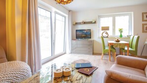 A living room with a sofa, a coffee table, and a television. There is a dining area with a table and chairs. - Reetdachhaus Kiek in` Wald (Zirchow/Usedom)
