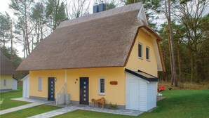 A yellow house with a thatched roof, a wooden bench, and a small garden area. - Reetdachhaus Kiek in` Wald (Zirchow/Usedom)