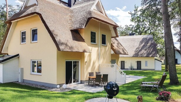 A yellow house with a thatched roof and a barbecue grill in the yard. - Reetdachhaus Kiek in` Wald (Zirchow/Usedom)