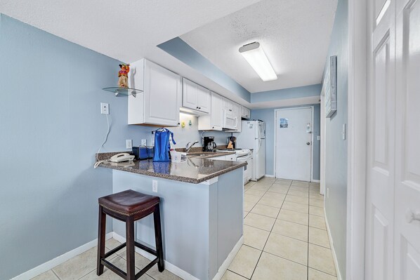 A kitchen with a central island, white cabinets, and a blue wall.