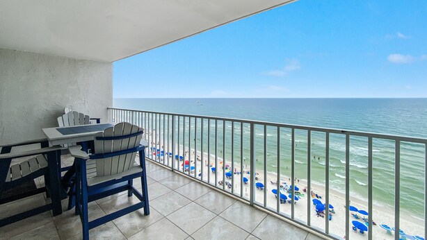 A balcony with a view of the beach and ocean.