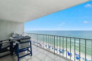 A balcony with a view of the beach and ocean.