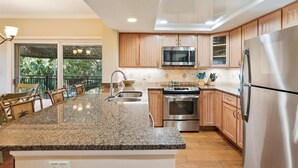 Eine moderne Küche mit Granit-Arbeitsplatten, Edelstahlgeräten und Holzschränken.
