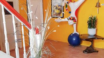 Ein Flur mit weißer Handläufe, einem Blumentopf, einer Skulptur und einem gerahmten Bild an der Wand.
