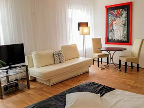 Una habitación de hotel moderna con sofá, televisión, una mesita y una silla.