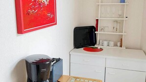 Una kitchenette con cafetera, tostadora y una pequeña mesa con bloc de notas.