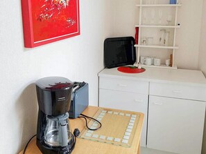 Une petite cuisine équipée d’une machine à café, d’un grille-pain et d’une petite table avec un bloc-notes.