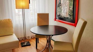Ein Zimmer mit einem runden Tisch, zwei Stühlen, einer Stehlampe und einem Bild an der Wand.