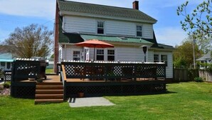 A two-story house with a covered deck and a red umbrella. - Blue Water - Single Family Home - In Town - LG. FENCEED IN YARD, NO LINENS (Chincoteague)