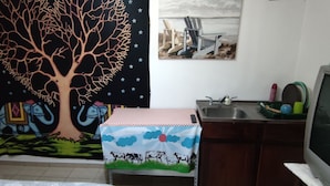 Una cocina con un lavamanos, una mesa con mantel a cuadros y un televisor.