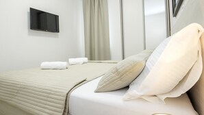 Een hotelkamer met een bed, een flatscreen televisie aan de wand, een raam met gordijnen en een schuifdeur.