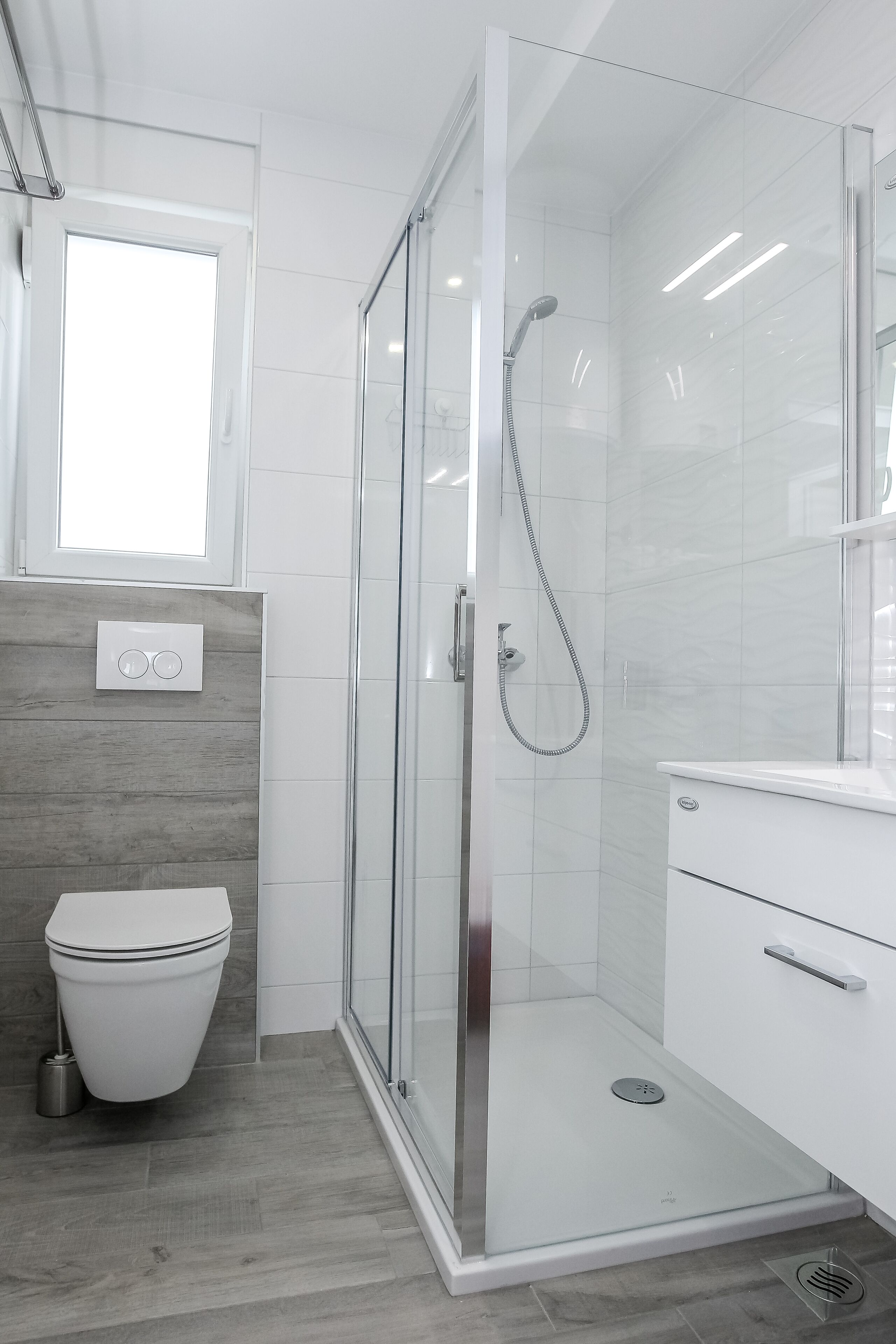 A modern bathroom with a glass-enclosed shower, a toilet, and a vanity with a mirror.