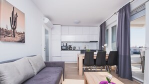 Een moderne woonruimte met een bank, eettafel, stoelen en een keuken.