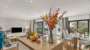 A modern living room with a wooden island, a flat-screen TV, and a dining area with a table set for a meal. - Villa Festina Lente in Makarska, heated pool (Makarska)