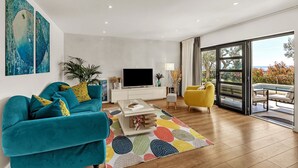 A modern living room with teal sofas, a yellow armchair, a flat-screen TV, and a large sliding glass door leading to an outdoor area. - Villa Festina Lente in Makarska, heated pool (Makarska)