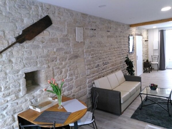 A living room with a stone wall, a sofa, a coffee table, and a fireplace.