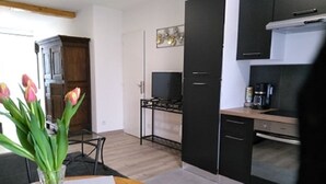 Ett modernt kök med svarta skåp, en gasspis och en kaffemaskin. Det finns ett matbord med en vas med blommor.